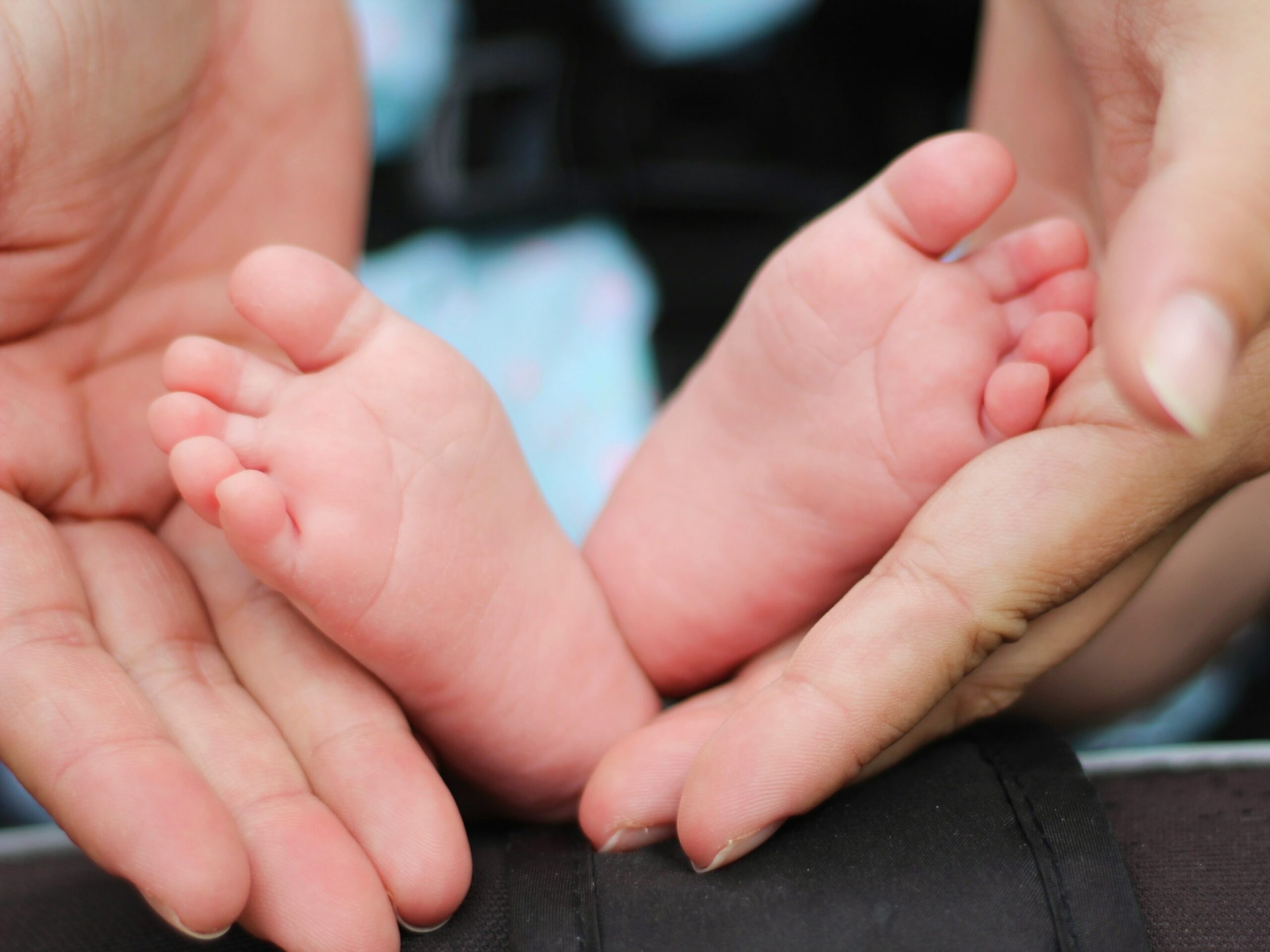 parent hands holding baby feet